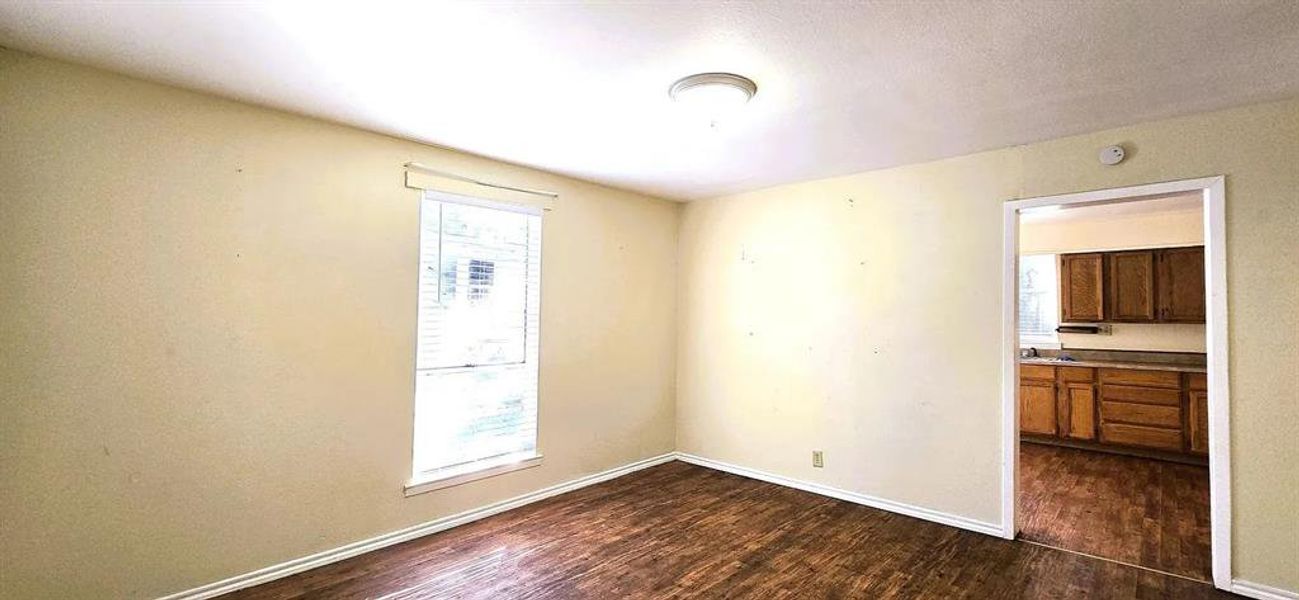 Spare room with baseboards and dark wood-type flooring