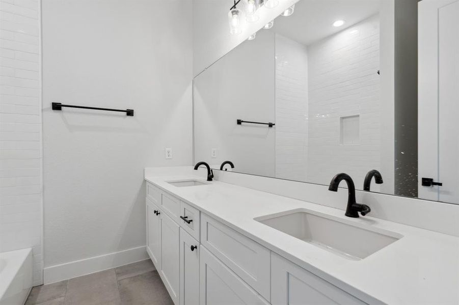 Double vanity sinks with matte black finishes create a timeless design while maximizing functionality of this shared bathroom.