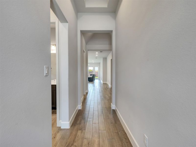 Bright and inviting hallway with elegant wood like tile flooring leads to a spacious living area, offering a seamless flow throughout the home.
