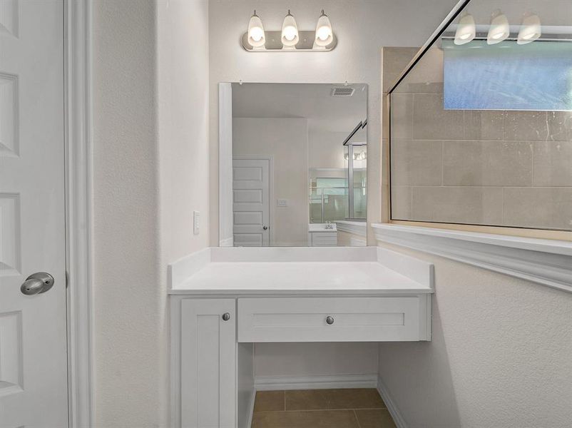 Bathroom featuring a tile shower, tile patterned flooring, and vanity