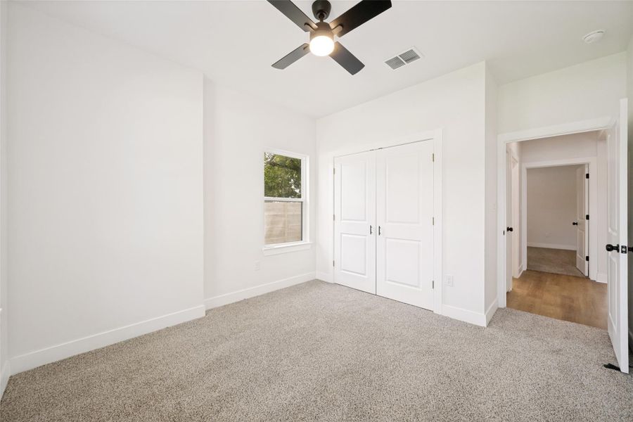 A well-lit bedroom features plush carpeting and a modern ceiling fan, offering a comfortable personal retreat. A well-lit bedroom features plush carpeting and a modern ceiling fan, offering a comfortable personal retreat.