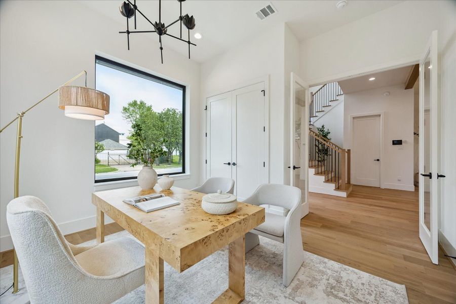 First-floor bedroom – features a designer lighting fixture, wood flooring, and a double French door. First-floor bedroom – features a designer lighting fixture, wood flooring, and a double French door.