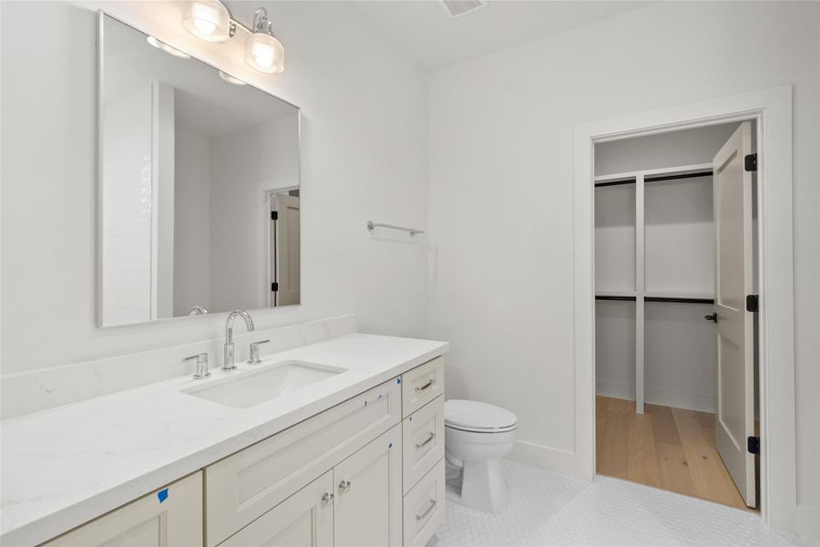 Your bathroom vanity anchors the space with sleek cabinetry, quartz countertops, and modern fixtures, creating a polished, functional setup for everyday routines. Just beyond, direct access to the walk-in closet makes mornings seamless—everything flows exactly the way it should.