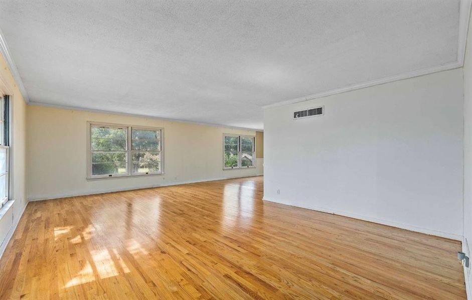 Spare room featuring crown molding, light wood finished floors, and a textured ceiling