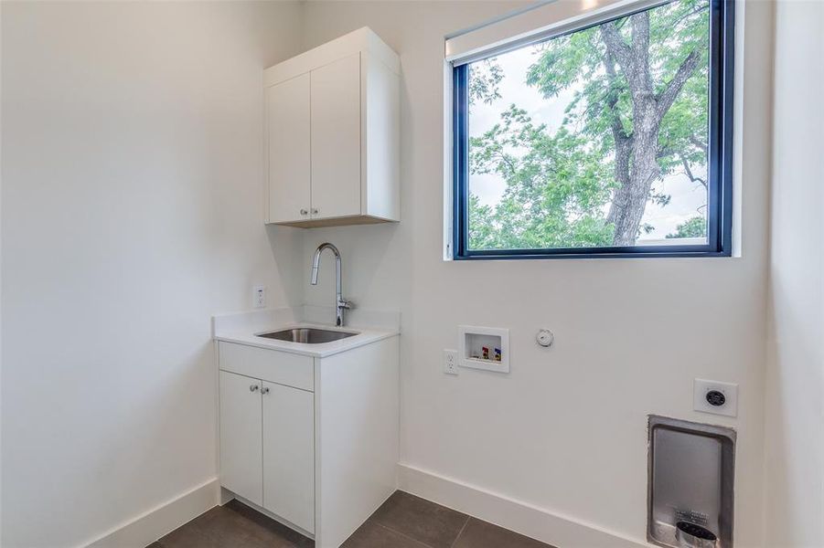 Full size utility room with sink and cabinet storage.