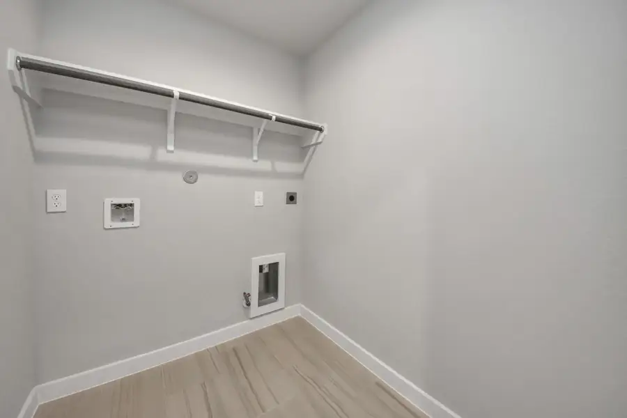 A perfect blend of functionality and comfort. Capture the essence of easy living with a first-floor laundry room, thoughtfully equipped with shelving for effortless organization. Bothelectric and gas connections available. Sample photo of completed home with similar floor plan. Actual colors and selections may vary.