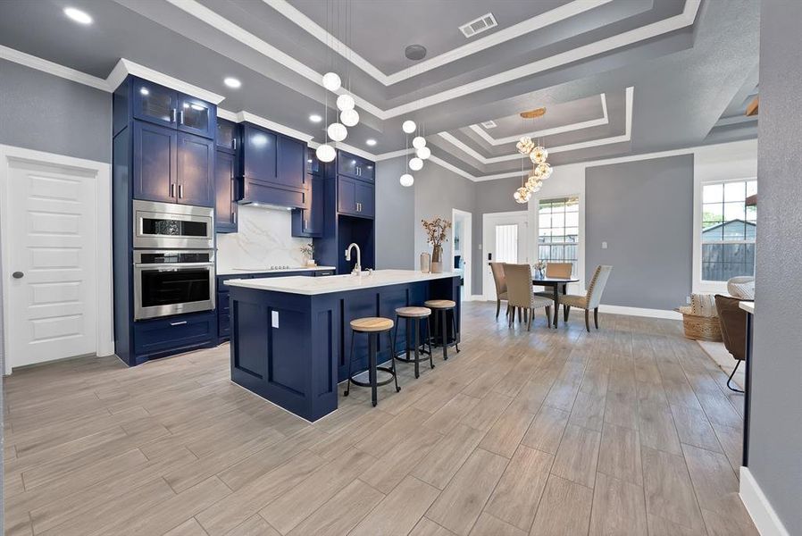 Kitchen featuring deep blue cabinetry, stainless steel built-in appliances, a white island countertop, and light wood-finish flooring