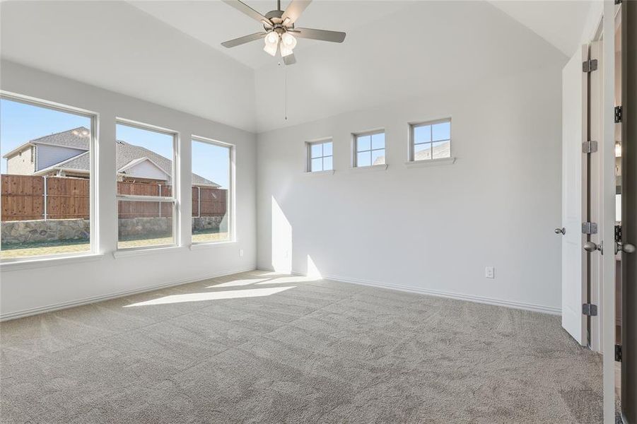 Unfurnished room with vaulted ceiling, light colored carpet, a ceiling fan, and plenty of natural light