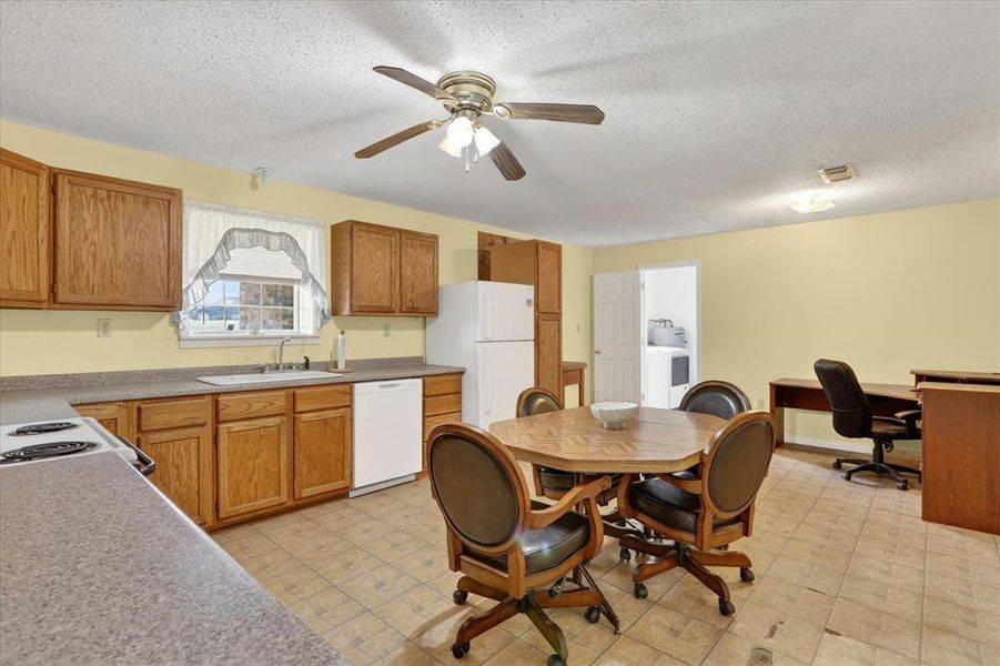 Open-concept kitchen featuring wood cabinetry, laminate countertops, a ceiling fan with integrated lighting, and tile flooring
