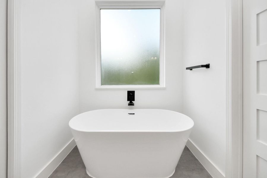 Primary bathroom w/ large soak in tub, frosted window for natural light.