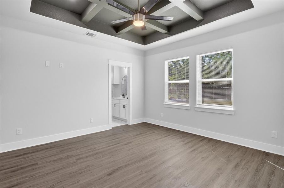 Wood-finish flooring throughout, featuring a tray ceiling with exposed beams and a ceiling fan