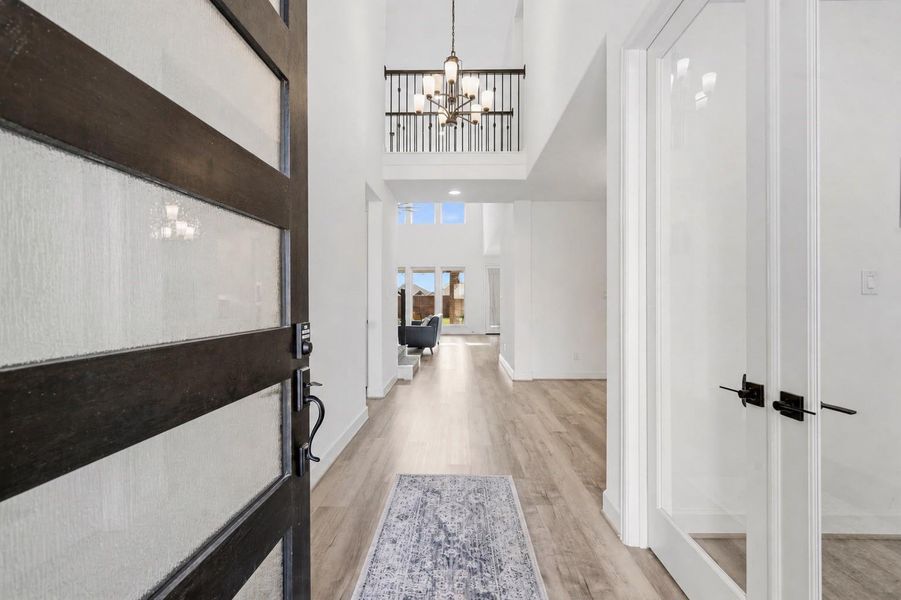 Walking in, you find a bright entryway with beautiful, wood like flooring that continues into the main living areas, making it easy to clean and maintain. Featuring glass French doors leading into the office and abundant natural light pouring into the foyer, this space sets the tone for the home's refined design and luxurious feel.