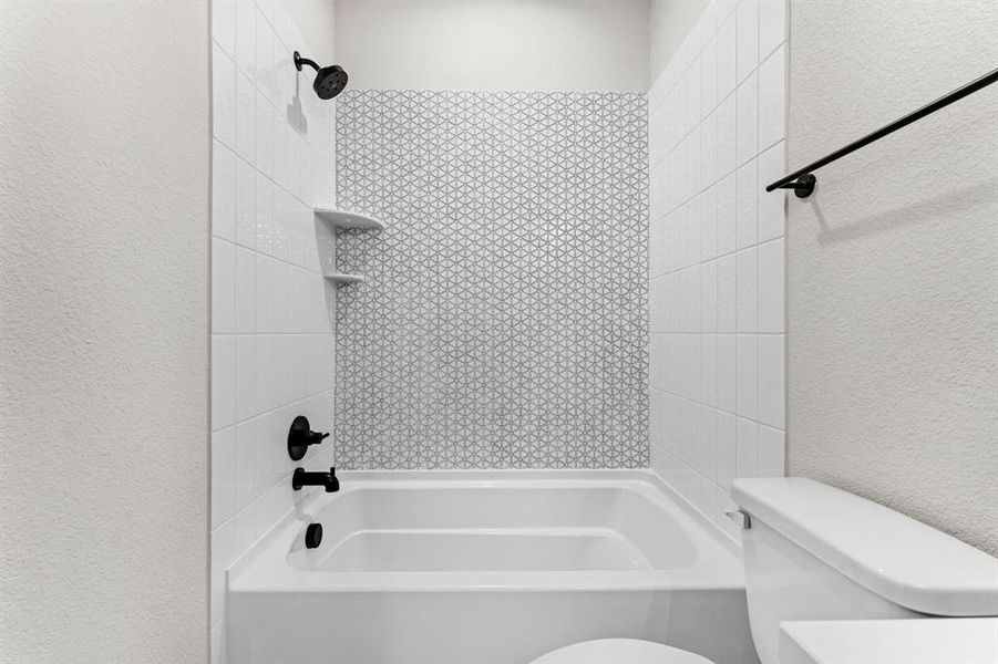 Bathroom featuring tiled shower / bath and toilet