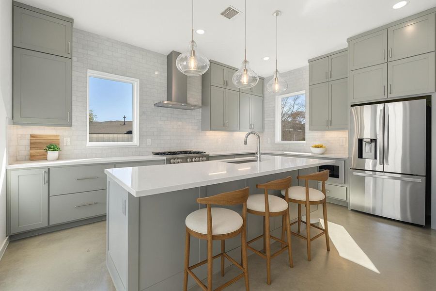 Kitchen with finished concrete floors, stainless steel fridge with ice dispenser, gray cabinets, decorative backsplash, and recessed lighting