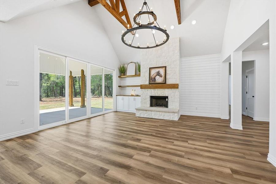 Unfurnished living room featuring a chandelier, a fireplace, lofted ceiling, and light wood finished floors