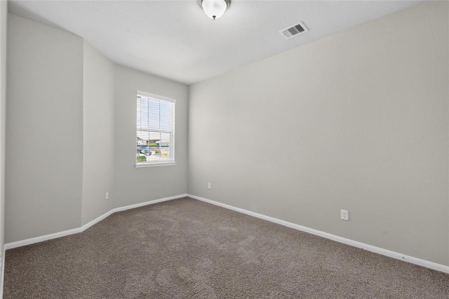 This photo shows a small, carpeted room with neutral-colored walls and a single window with blinds. It features a white door with brass handles, and a ceiling light fixture, offering a clean and simple space that can be used as a bedroom or office. This photo shows a small, carpeted room with neutral-colored walls and a single window with blinds. It features a white door with brass handles, and a ceiling light fixture, offering a clean and simple space that can be used as a bedroom or office.