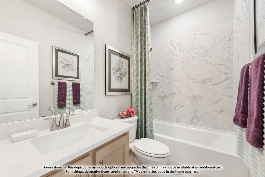 Bathroom with white quartz vanity, toilet, and tub-shower combo with marble-look tile surround and green curtain.