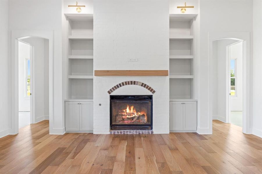 Unfurnished living room featuring light hardwood / wood-style flooring, built in features, and a fireplace