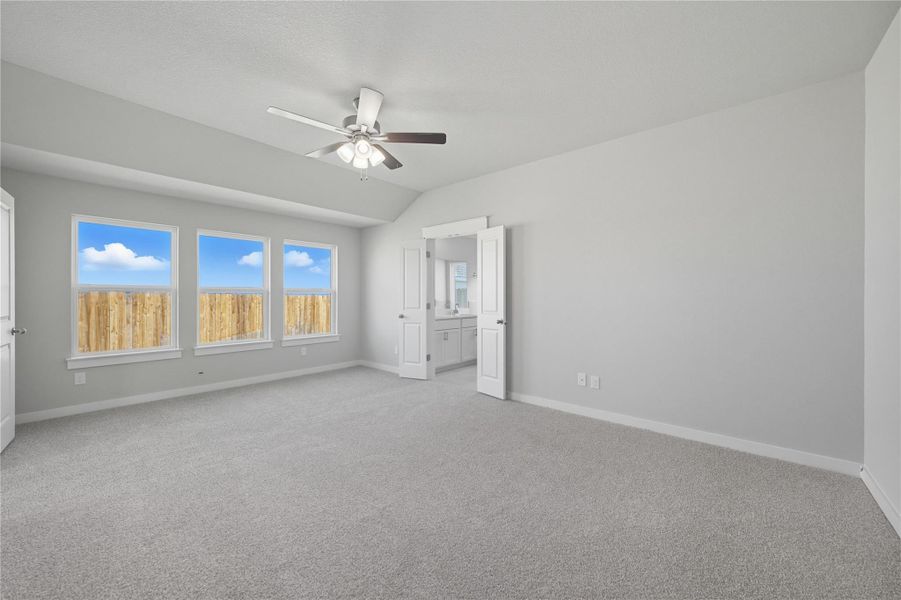 Unfurnished bedroom featuring light colored carpet, lofted ceiling, ceiling fan, and ensuite bathroom Unfurnished bedroom featuring light colored carpet, lofted ceiling, ceiling fan, and ensuite bathroom