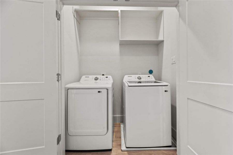Sleek laundry nook with modern washer, dryer, and overhead shelving in a pristine white closet for easy organization.