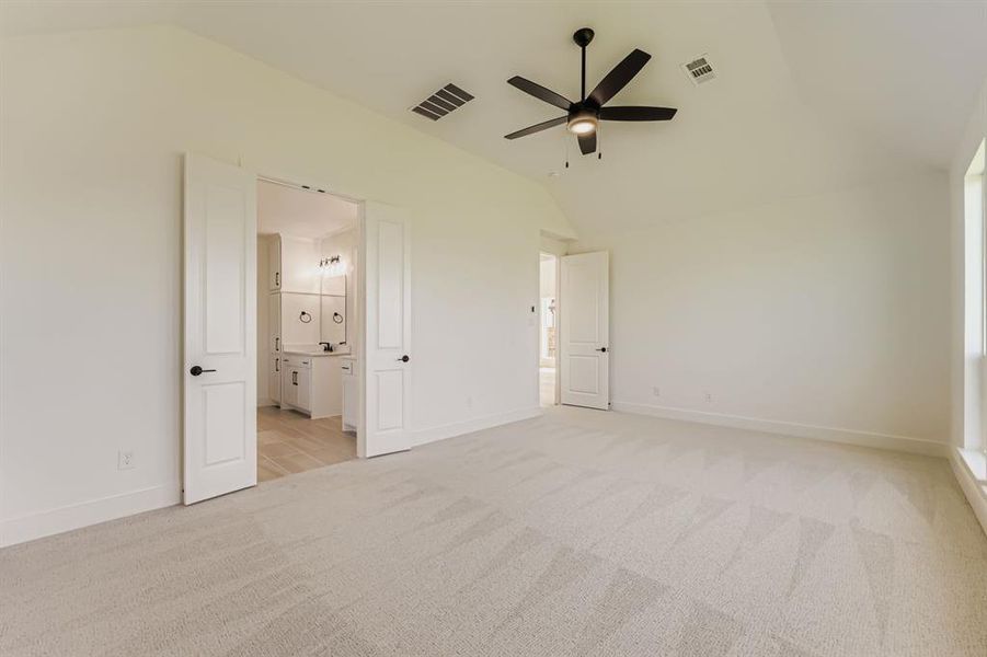 Unfurnished bedroom featuring light carpet, vaulted ceiling, and ceiling fan