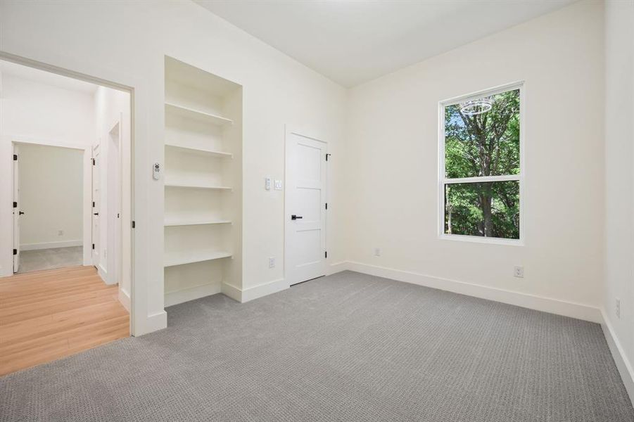 First floor bedroom featuring light carpet and a bookcase.