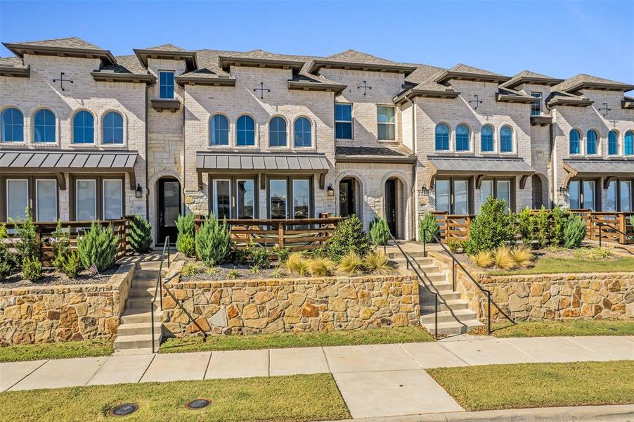 View of front facade featuring brick siding, a shingled roof, a standing seam roof, and stone siding
