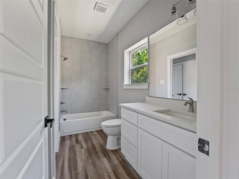 Bathroom featuring toilet, wood finished floors, vanity, and bathing tub / shower combination