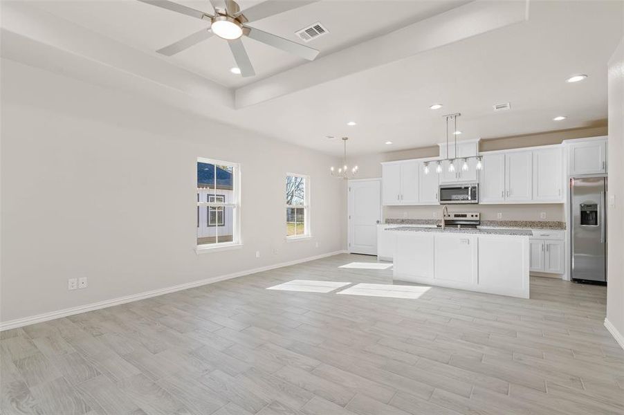 Kitchen with light hardwood / wood-style flooring, white cabinets, pendant lighting, and appliances with stainless steel finishes