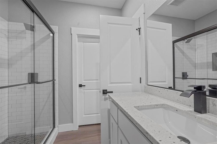 Bathroom with vanity, hardwood / wood-style floors, and a shower with door