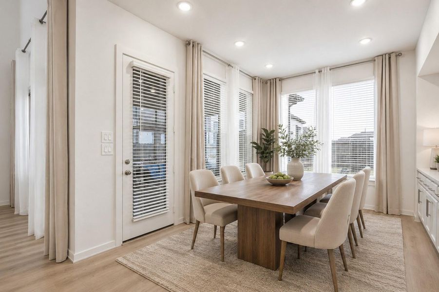 The dining room features rich wood flooring, multiple windows with privacy blinds, and built-in cabinets, creating a bright and sophisticated space perfect for hosting and entertaining. *virtually staged
