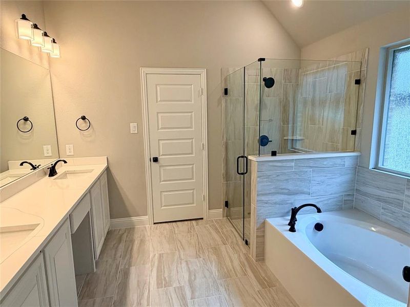 Spa-like master bath with separate tub & shower with tile pan & frameless glass. Calacatta Lincoln quartz counters, white cabinets, and 12x24  tile on walls & floor.