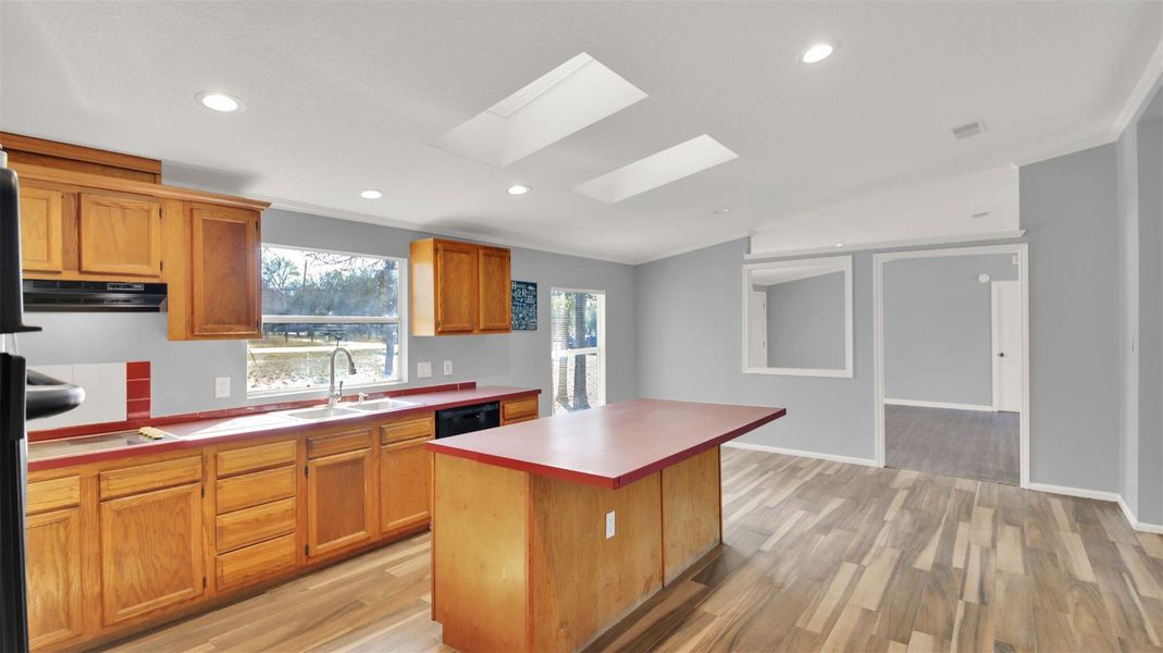 Kitchen with a skylight, a center island, light wood finished floors, recessed lighting, and vaulted ceiling