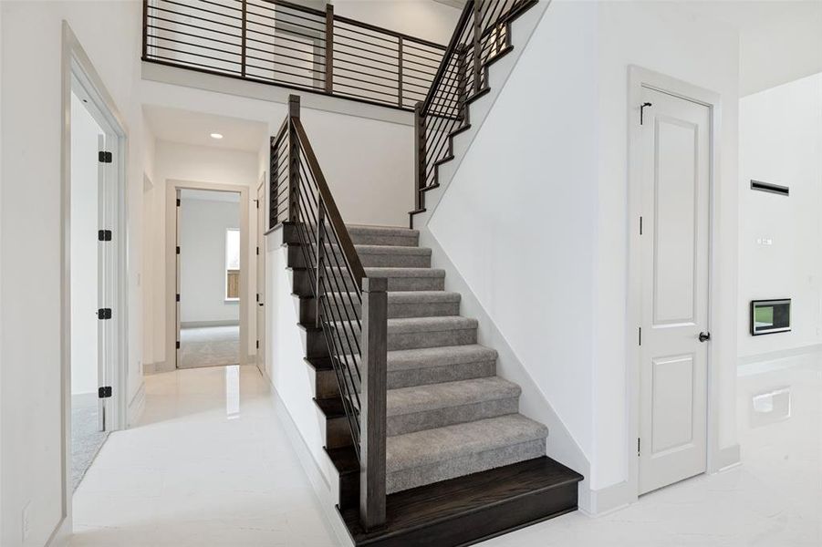 Modern staircase featuring wood-finish treads, carpeted risers, and horizontal metal balusters Modern staircase featuring wood-finish treads, carpeted risers, and horizontal metal balusters