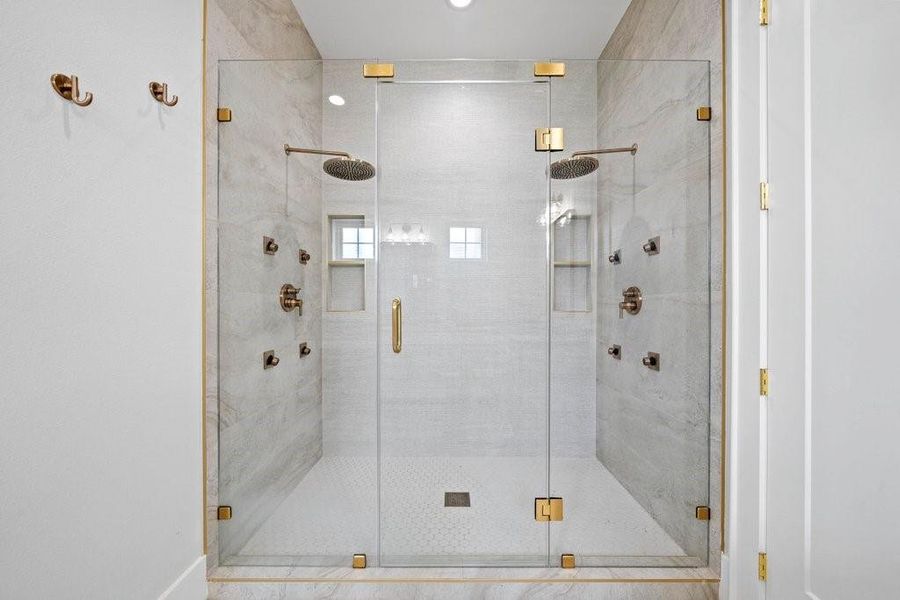 Indulge in a spa-like experience with this oversized frameless glass shower, featuring dual rain showerheads, multiple body sprays, and elegant gold accents—designed for the ultimate in daily relaxation and comfort.