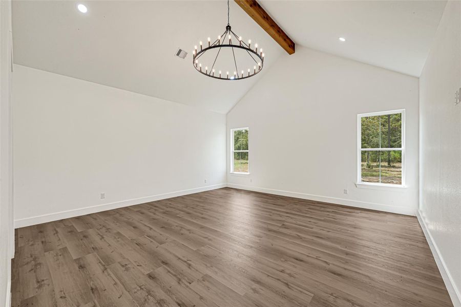 Primary bedroom with vaulted ceilings, wood beam and chanderlier