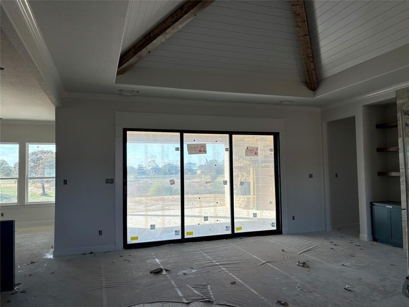 Unfurnished living room with crown molding and lofted ceiling with beams