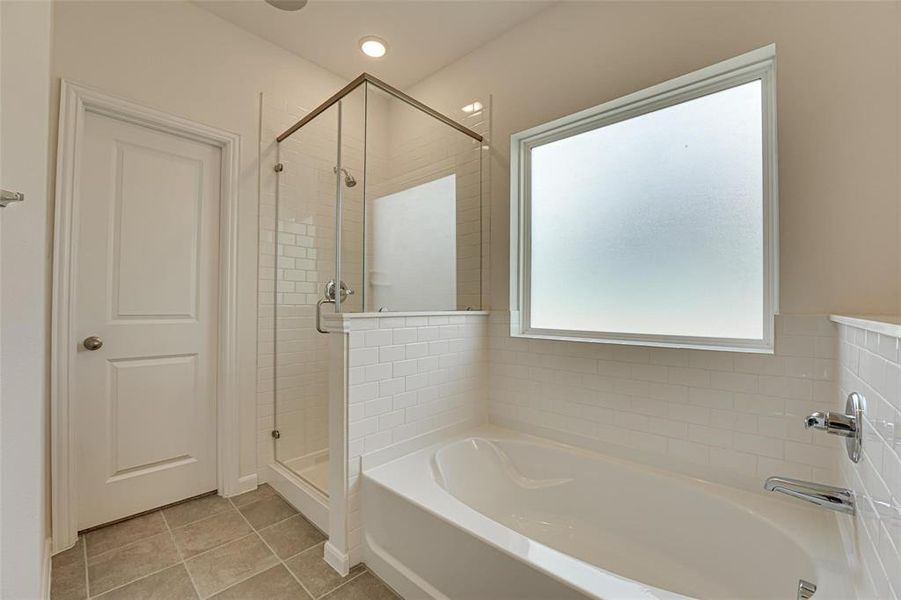 Bathroom with shower with separate bathtub and tile patterned floors