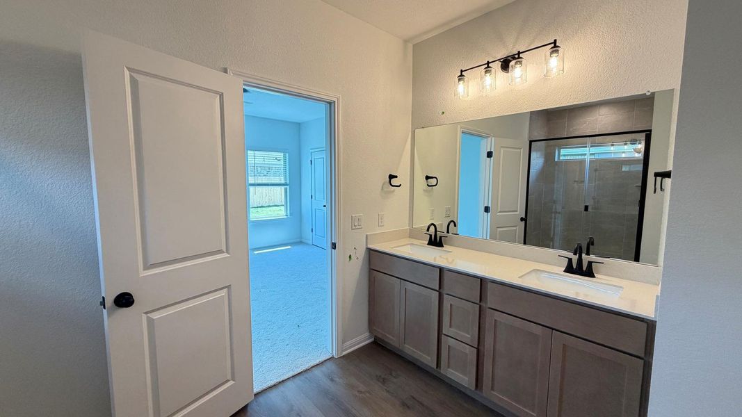Double vanity with sleek fixtures anchors this functional and contemporary primary bathroom. Double vanity with sleek fixtures anchors this functional and contemporary primary bathroom.