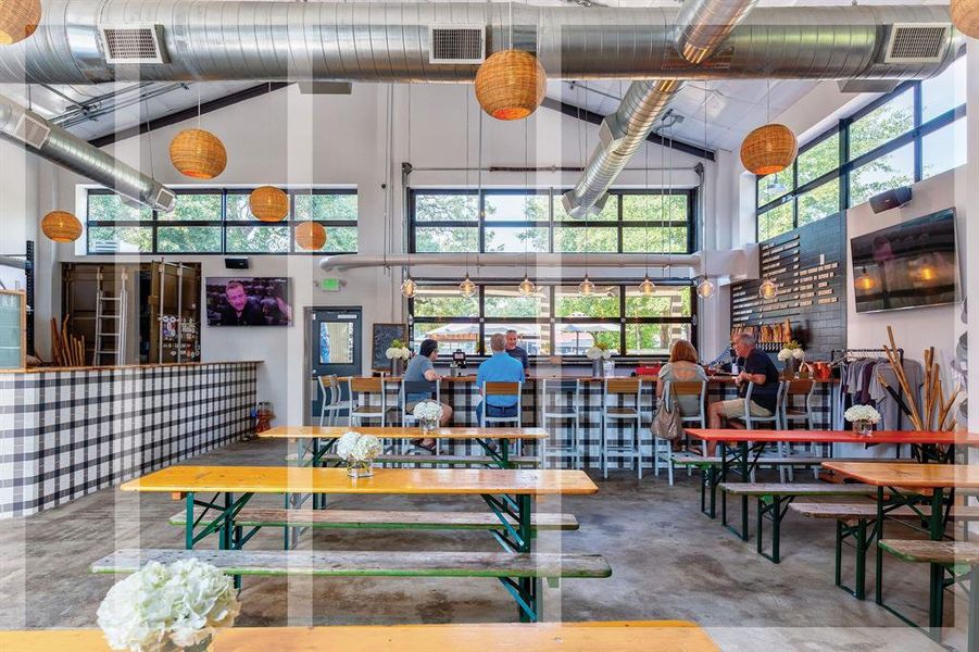 Walls of windows infuse illumination throughout the industrial interior, creating a dynamic warehouse interior that hosts the 10-barrel brewery.