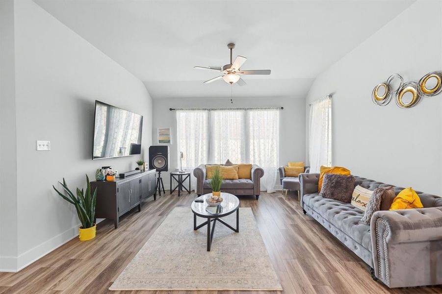Living room featuring vaulted ceiling, light wood-style floors, and a ceiling fan Living room featuring vaulted ceiling, light wood-style floors, and a ceiling fan
