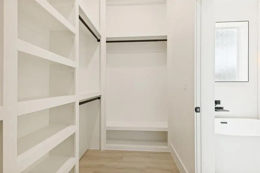Walk-in closet with built-in shelving, two hanging rods, and a storage bench Walk-in closet with built-in shelving, two hanging rods, and a storage bench