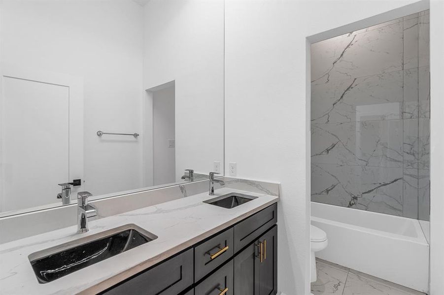 Full bathroom with tiled shower / bath combo, tile flooring, dual vanity, and toilet