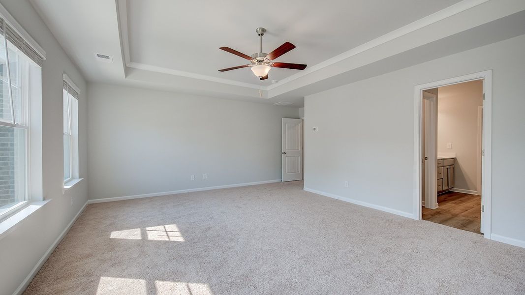 Spacious Ridgewood primary suite with tray ceiling, carpet flooring, and neutral modern finishes at Bowers Farm.