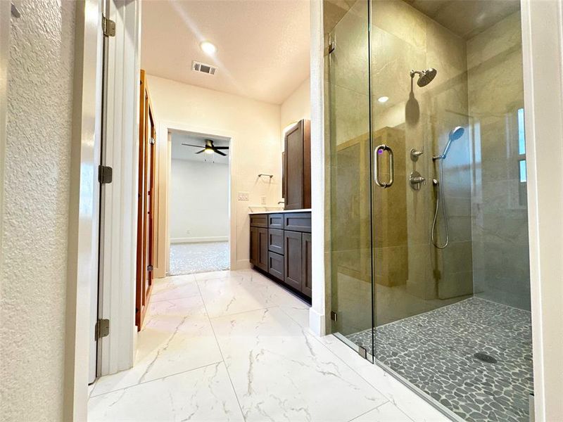 Bathroom with a shower stall, marble finish floor, vanity, and visible vents