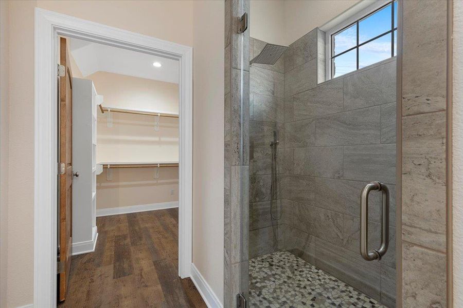 Full bath featuring a stall shower, wood finished floors, and a walk in closet
