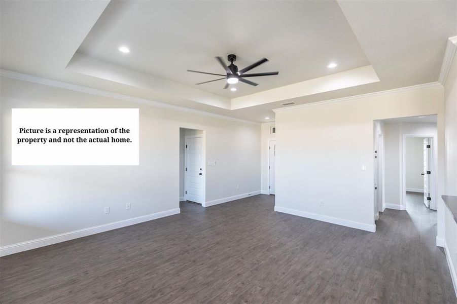 Spacious room featuring wood-finish flooring, a tray ceiling with recessed lighting, and a contemporary ceiling fan