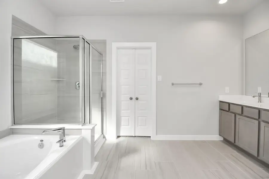 Indulge in a spa-like retreat within the confines of this primary bathroom.Delight in a spacious walk-in shower enveloped in stylish tile surround, unwindin a separate garden tub adorned with custom detailing, and elevate your dailyroutine at the elegant vanity. Sample photo of completed home with similar floor plan. Actual colors and selections may vary.