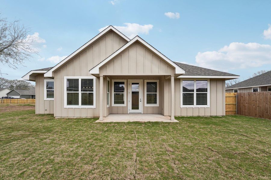 Back of property with a patio area, a yard, board and batten siding, and fence