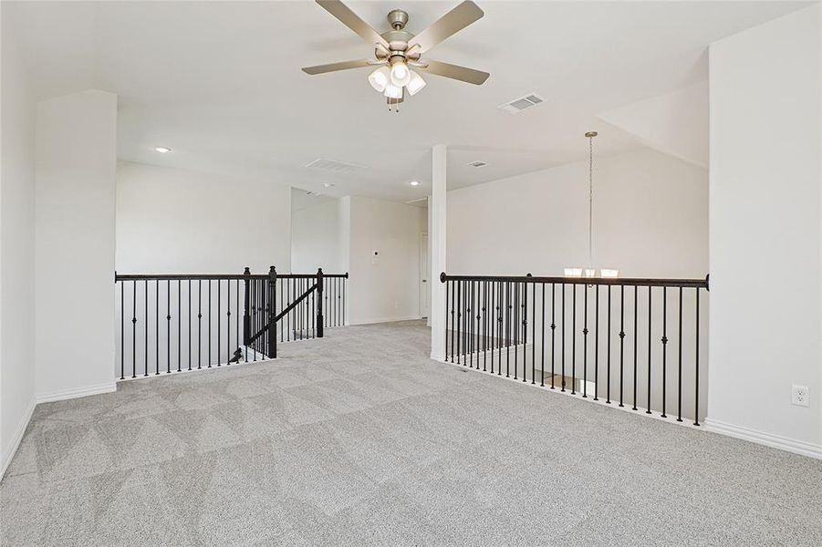 Empty room with light carpet and ceiling fan with notable chandelier